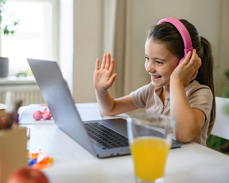 Elev med rosa hörlurar via laptop